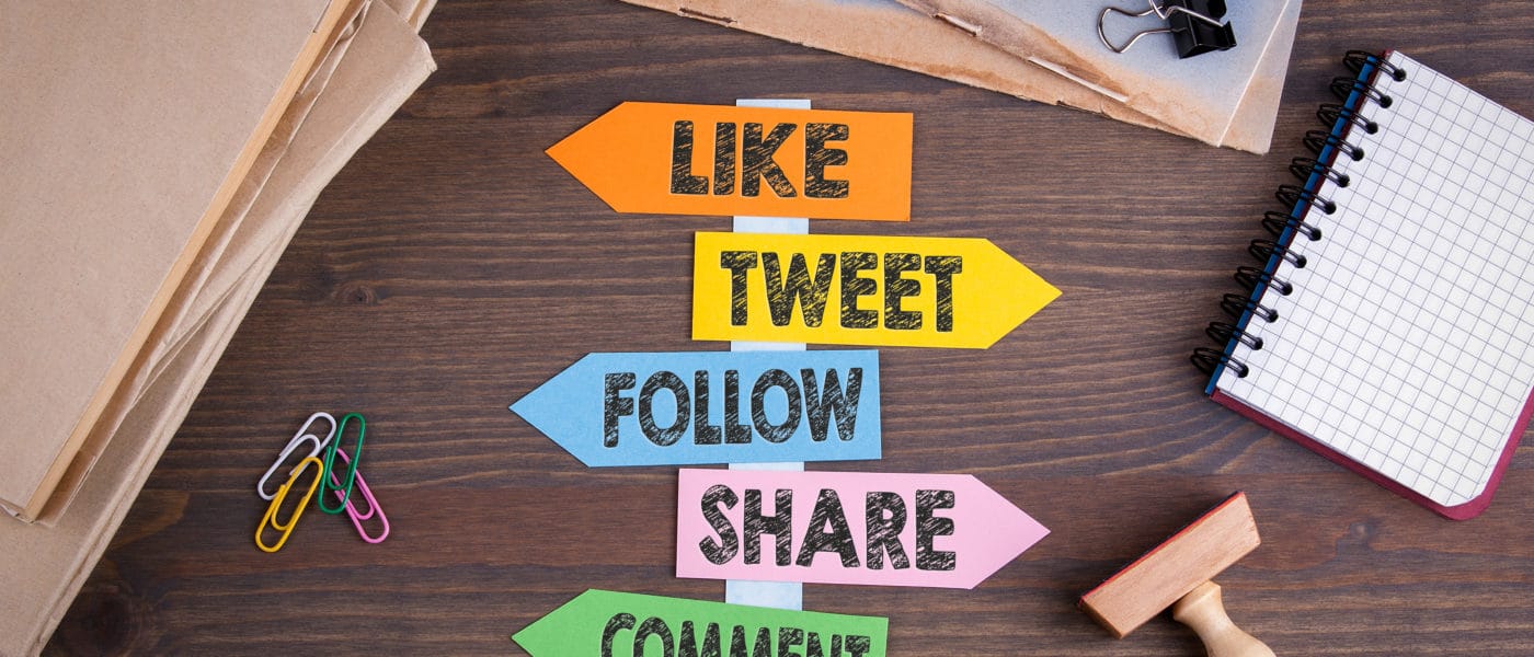 social media concept (like, tweet, follow, share, comment). Paper signpost on a wooden desk