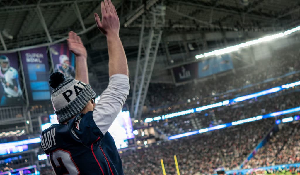 Fan at the super bowl with his hands in the air for a touchdown.