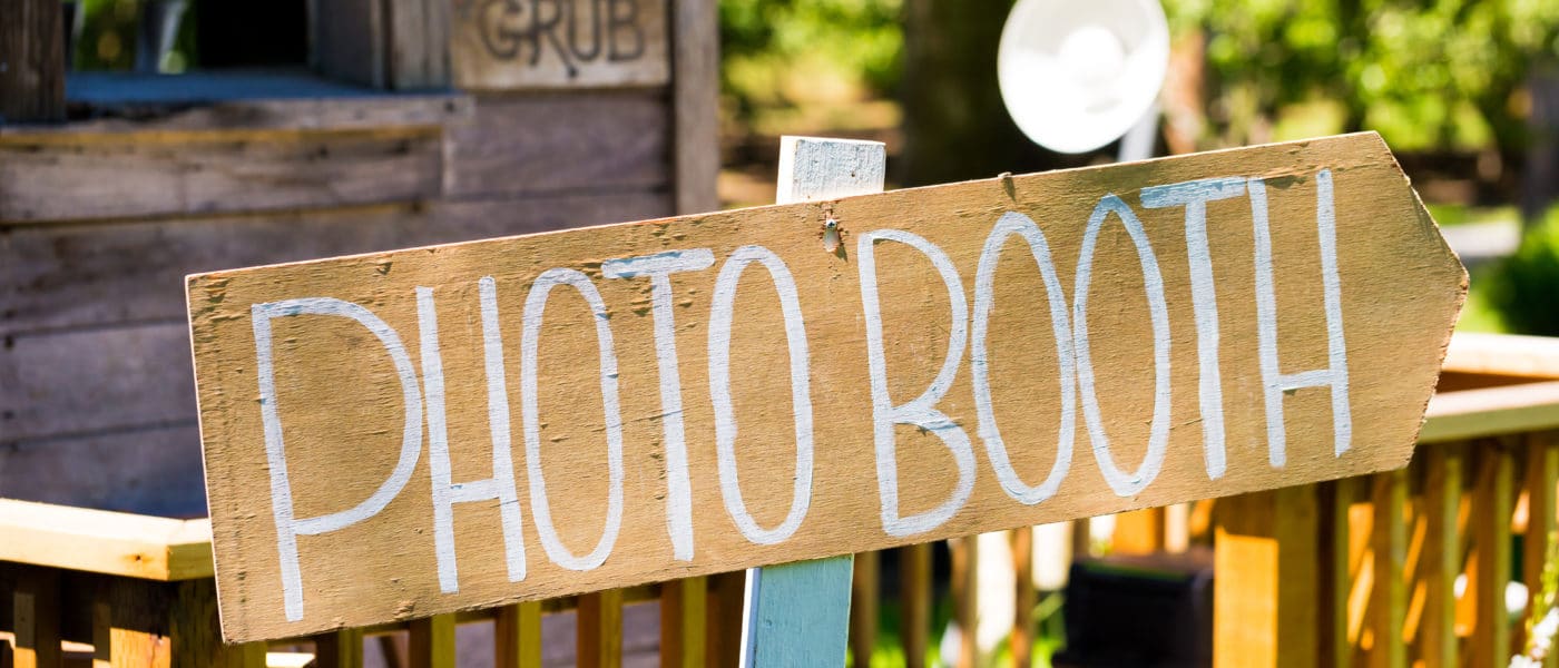 Sign that says photo booth at an outdoor wedding reception.