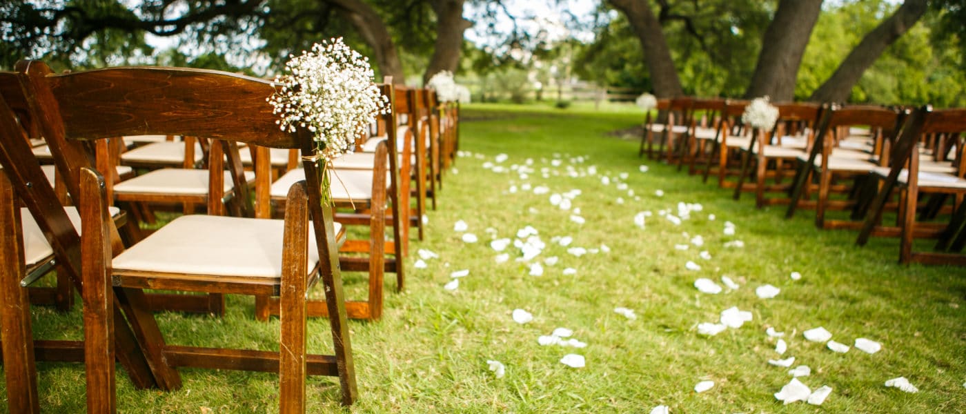 Outdoor wedding setup with flower petals going down the aisle.